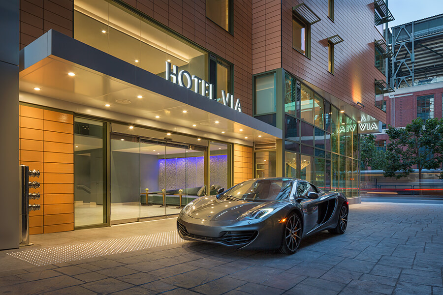 A mclaren sports car parked in front of a boutique hotel.