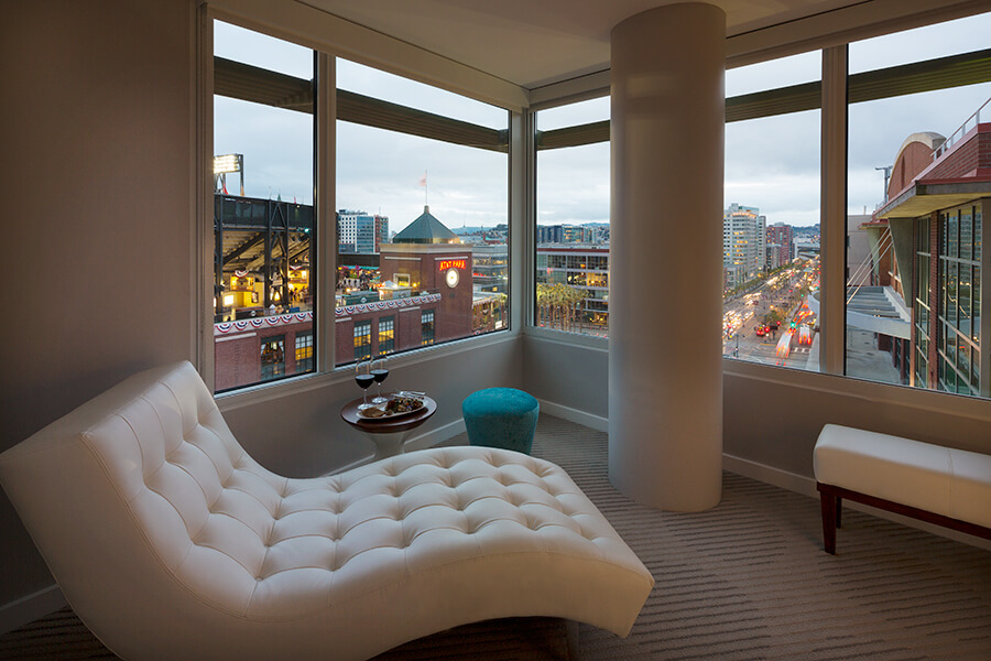 A white chair in a room with a view of a city. Located at a hotel near Oracle Park, this versatile white chair provides comfort and style for guests to relax while enjoying the breathtaking sights