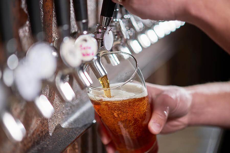 A person pouring a beer into a glass at a boutique hotel in South Beach, San Francisco.