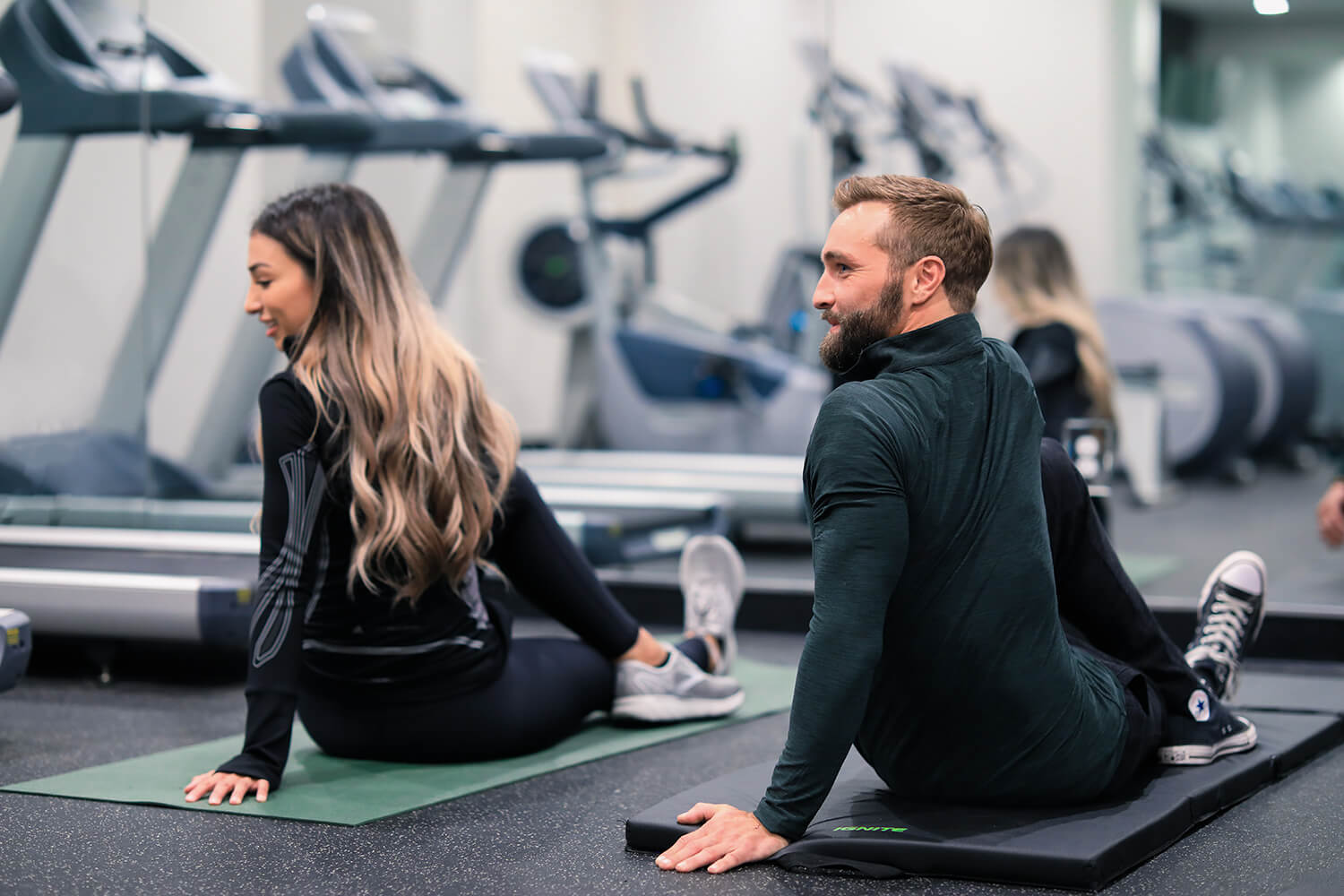 A man and a woman engaged in exercises at a gym.