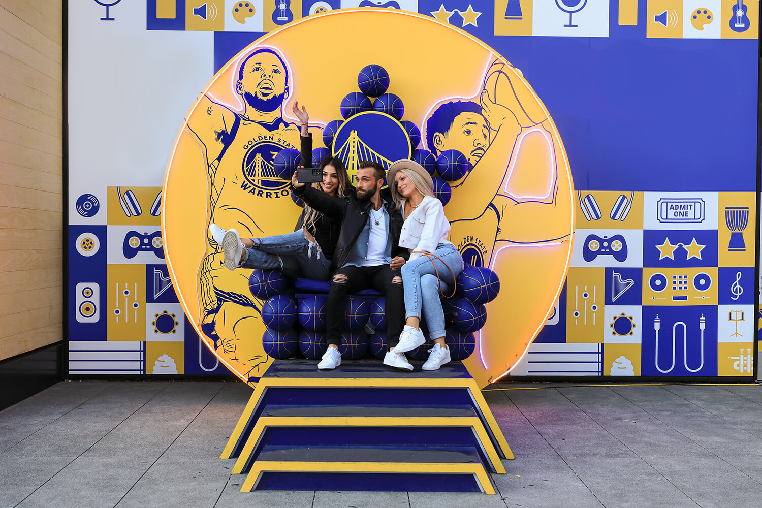 Two women sitting on a throne in front of a golden State Warriors logo at a boutique hotel near Oracle Park.