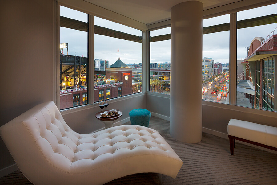 A white chair in a boutique hotel room with a view of a city.