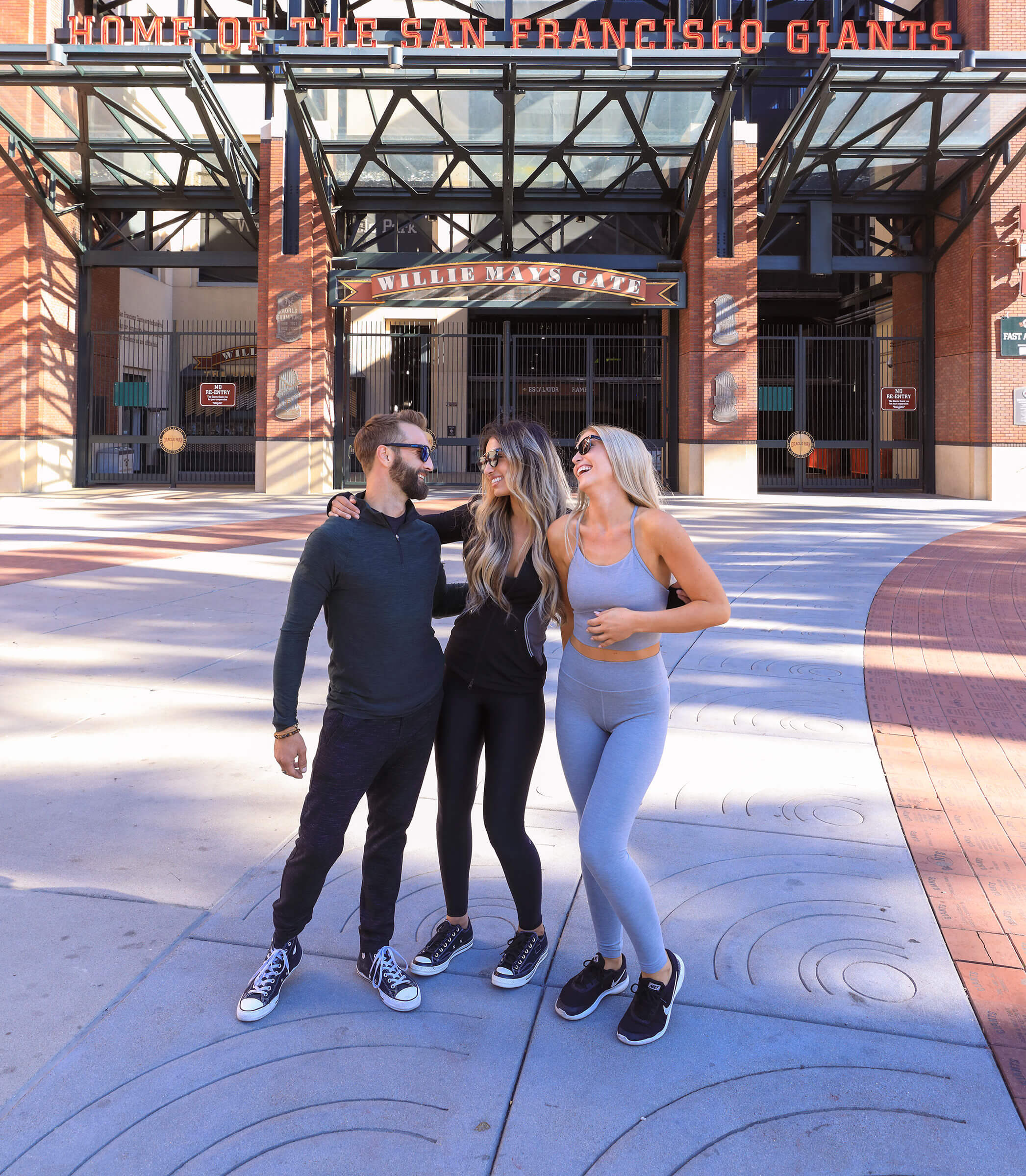 Three people posing in front of the San Francisco Giants stadium, near the South Beach San Francisco hotel.